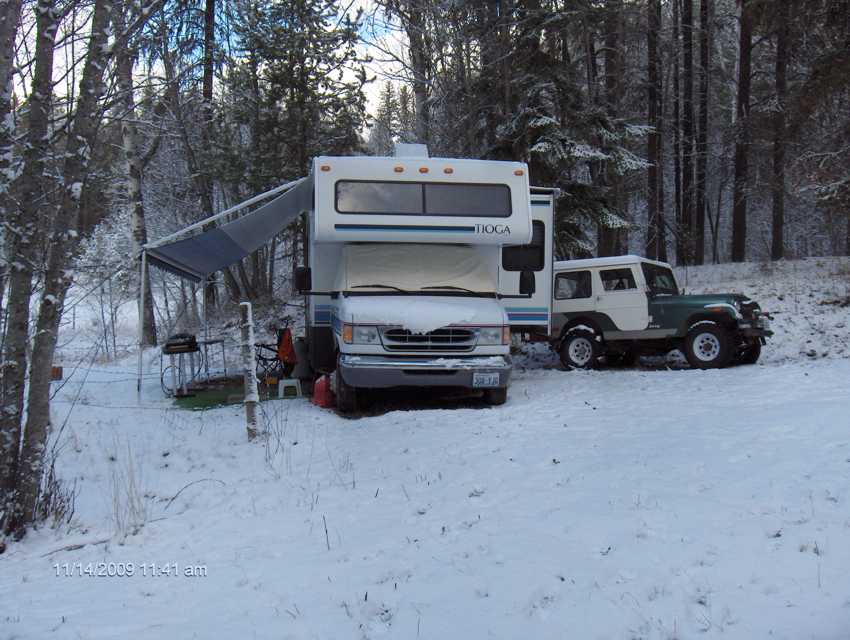 Looking at the front of the motoer home and Jeep in the snowy camp.