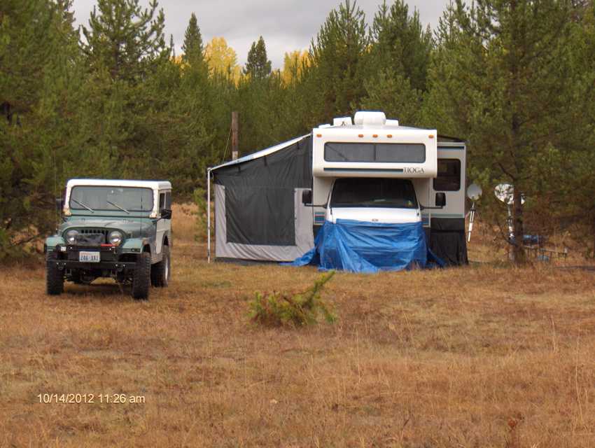 Looking at the front of the motor home and Jeep with the awning enclosure and stove.