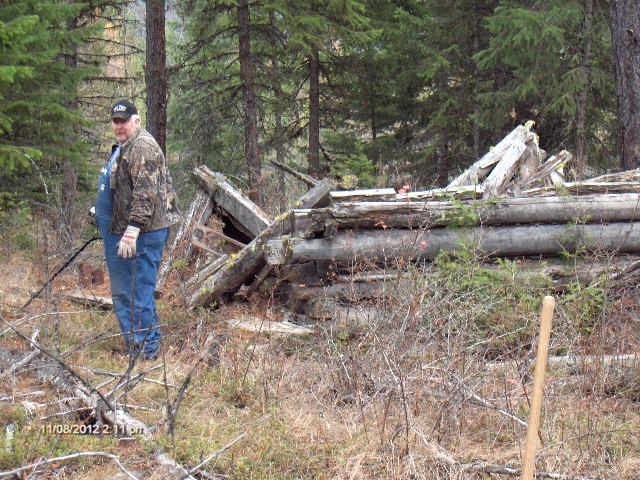 Les with his metal detector near ruins to a cabin.